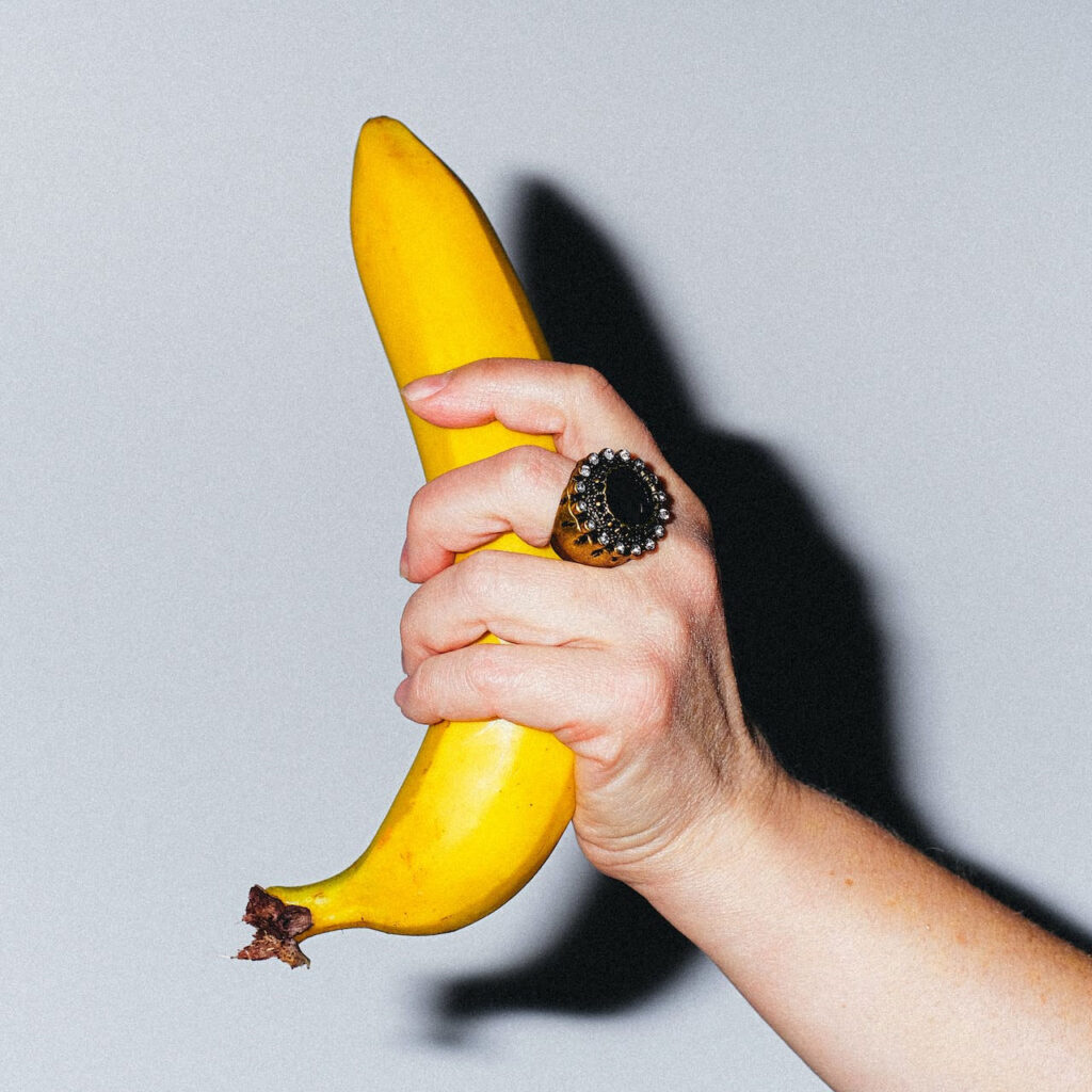 a hand holding a banana to illustrate solo masturbation